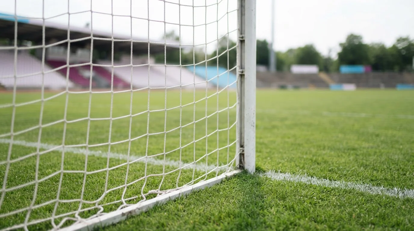 Fußballtor und Netz am Rand eines grünen Spielfelds
